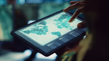 Navy operations specialist examines a world map with gps system on his tablet, working on finding tracks of enemy vessels. General employs government satellite data for missions. Close up. Camera A.
