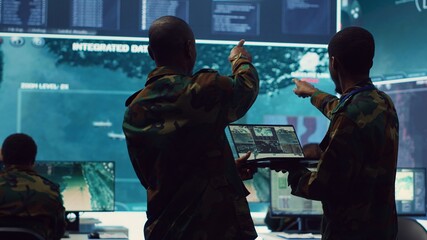 Intelligence analysts supervising and coordinating the big data analysis, processing tactical information to help the field troops. Officers monitoring real time warfare information. Camera A.