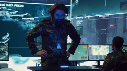 Infantry unit leader studies satellite imagery on a holographic image, working with high tech...