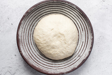 Overhead view of bread dough rising in banneton basket , top view of proofing dough in a wood proofing basket, process of making artisan bread