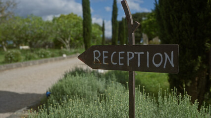 An outdoor reception sign in a lush garden with a gravel path, indicating a serene and welcoming setting.