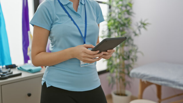 A female healthcare professional is using a tablet in a well-equipped rehabilitation clinic's room. - Powered by Adobe