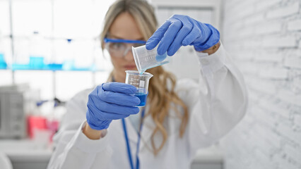 A focused woman scientist conducting experiments in a laboratory, pouring a blue chemical substance into a beaker.