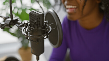 Smiling african american woman in studio with microphone for radio or music recording.