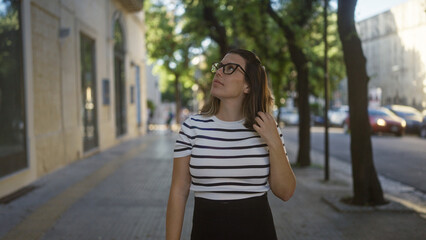 Obraz premium A beautiful young hispanic woman wearing glasses walks thoughtfully through the streets of lecce, puglia, italy, on a sunny day.