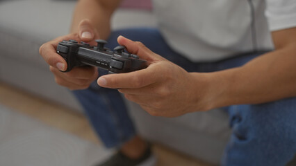 Close-up of a young hispanic man playing with a game controller indoors, illustrating leisure time...