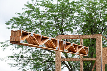 Residential house construction, boom crane lifting lumber delivery, support truss beams, to next...