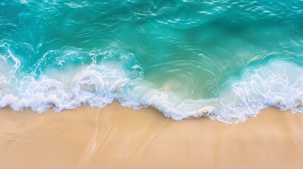 An aerial view captures the gentle embrace between the azure waves and the soft sandy beach, creating a tranquil and picturesque scene 