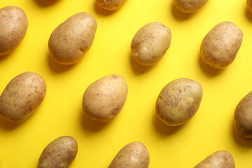 Many fresh potatoes on yellow background, flat lay