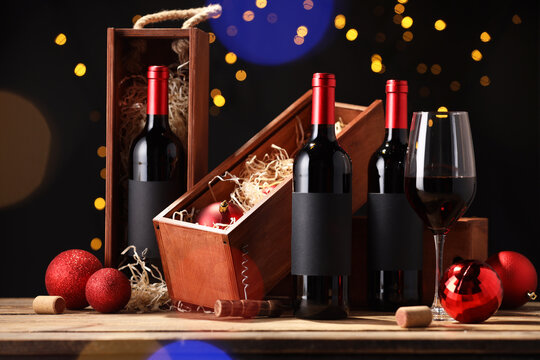 Bottles of wine, glass, wooden boxes, corks and red Christmas balls on table