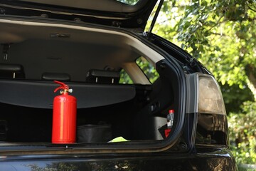 Red fire extinguisher in trunk. Car safety equipment
