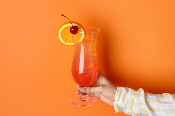 Woman with glass of refreshing cocktail on orange background, closeup