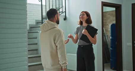 Happy girl realtor in round glasses gives a bunch of house keys to a guy after making a deal about selling a house and shaking hands