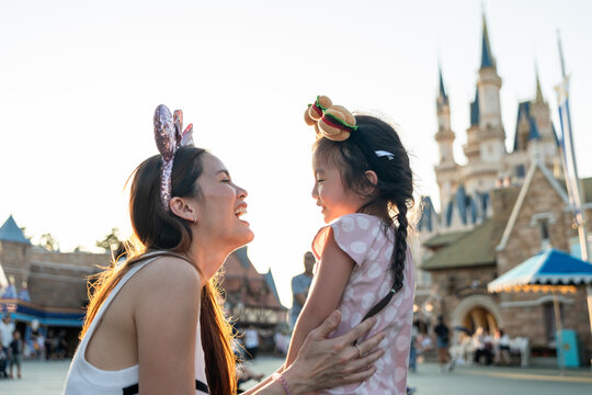 Asian mother and adorable kid daughter traveling at the theme park. 