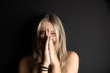 portrait of a woman smiling with hands in front of face