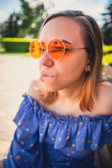 Thoughtful Young Woman in Floral Blouse Enjoying a Sunny Day Outdoors in a Park
