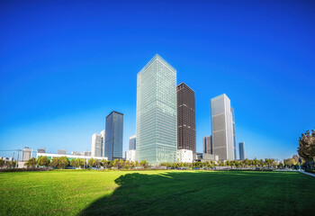 Obraz premium Lush Greenery Fronting Towering City Skyscrapers