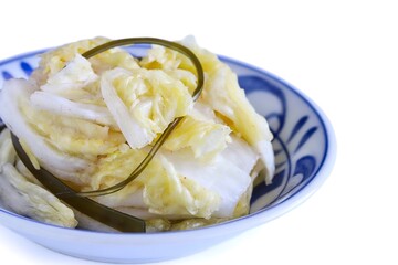 A close up shot of Japanese style pickled Chinese cabbage on a porcelain plate on white background.
