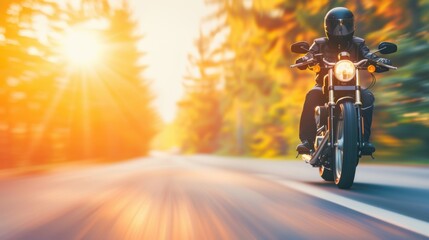 Naklejka premium A motorcyclist glides down a quiet road, surrounded by trees, as the sun sets