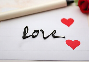 Word Love hand written on white paper with red hearts. Handwritting letters for Valentine's Day. Romantic concept. Lovely drawing