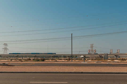 Road traffic signs with elevated metro train and industrial background on a clear day