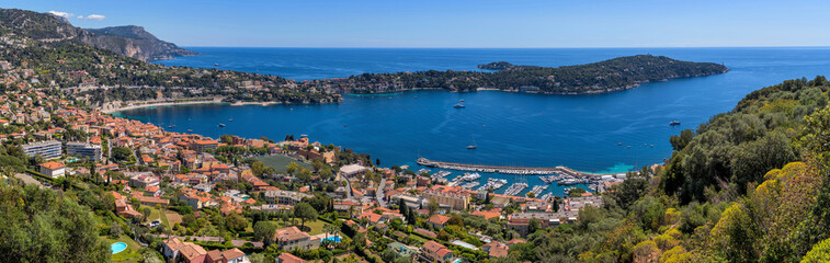 Fototapeta premium Seaside Resort - A panoramic overview of French resort town Villefranche-sur-Mer and its deep blue bay at coast of Mediterranean Sea on a sunny Spring morning. French Riviera, France, Europe.