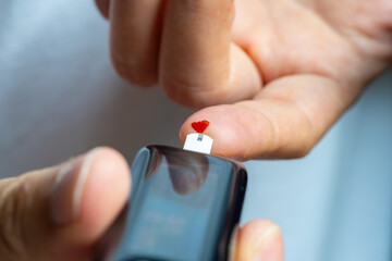 Woman's hands checking diabetes and hyperglycemia with digital blood sugar meter. Healthcare and...