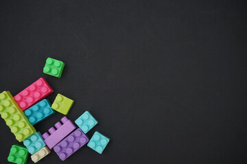 Frame of Bricks building block toys on dark black sheet background. Banner for kids toys shop. Flat lay, top view, copy space.