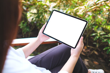 Mockup image of a woman holding digital tablet with blank white desktop screen in the outdoors