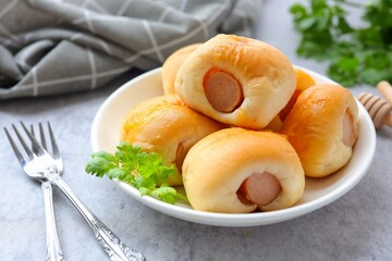 Sausage mini bun in a white plate with fork on cement background