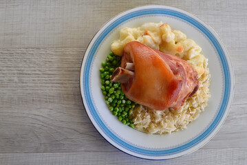 German style pork knuckle with sauerkraut cauliflower bake and green peas.