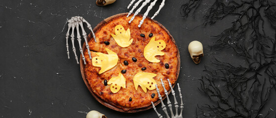 Wooden board with tasty pizza and decorations for Halloween party on black background