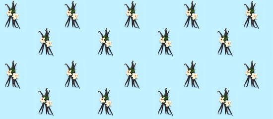 Aromatic vanilla sticks and flowers on blue background