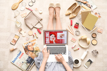Woman with laptop, makeup products and accessories shopping online on beige carpet