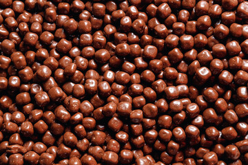 Closeup brown dragee, chocolate covered nuts, sweet candy background