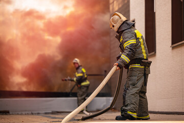 Fire incident in building. Action photo fireman team extinguishes burn with hose water