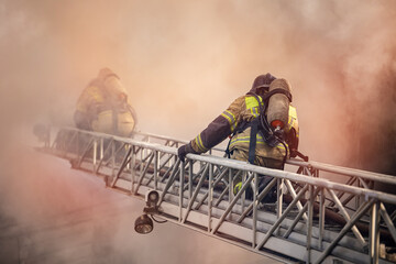 Firefighters climb ladder into burning house through smoke to rescue people and extinguish fire © Parilov
