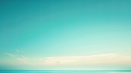 Fototapeta premium Serene Azure Horizon: A tranquil and minimalist landscape photo of a vast, azure sky meeting the ocean horizon, with delicate white clouds painting the sky.