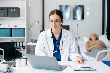 Young female doctor in white medical uniform using laptop and tablet talking video conference call at desk,Doctor sitting at desk and writing a prescription for her patient