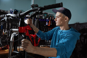 Handsome young man mechanic repairing bike working at bicycle workshop - Powered by Adobe