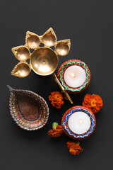 Diya lamps with candles and marigold flowers on black background. Divaly celebration