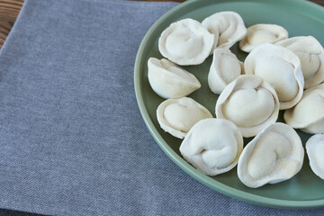 Homemade dumplings on a green plate on a gray background