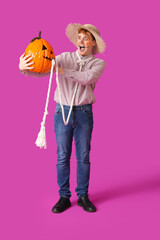 Scared young man dressed for Halloween with pumpkin on color background