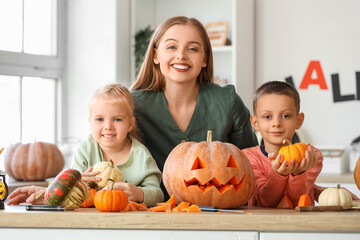 Fototapeta premium Happy mother with her little children and Halloween pumpkins in kitchen