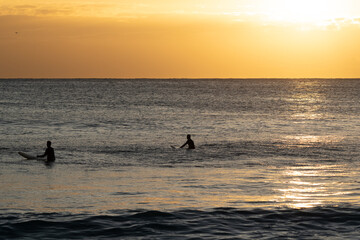 Fototapeta premium Two silhouette surfers at sunrise on there surfboards in the ocean 
