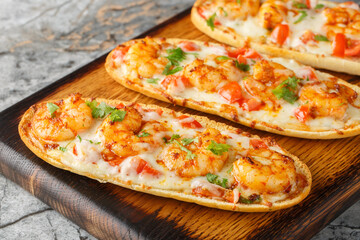 Mozzarella shrimps open sandwiches baked on Italian garlic bread close-up on a wooden board on the table. Horizontal