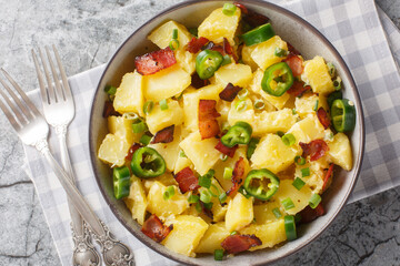 Creamy potato jalapeno salad with bacon, green onions and mayonnaise close-up in a bowl on the table. Horizontal top view from above