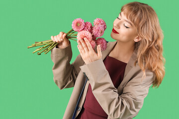Stylish young woman in fall clothes with flowers on green background
