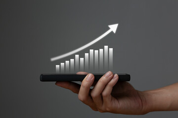 Businessman holding a smartphone or mobile phone with a business growth diagram business economics technology concept