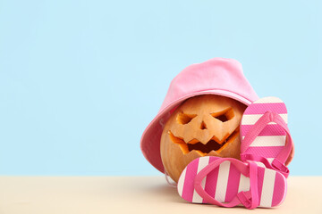 Carved pumpkin for Halloween with stylish hat and flip-flops on blue background